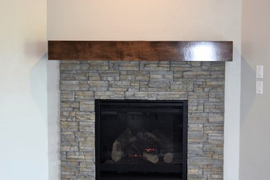 Example of a huge open concept medium tone wood floor and brown floor game room design in Other with a corner fireplace and a stone fireplace