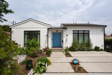 Photo of a medium sized and white farmhouse bungalow detached house in Los Angeles with concrete fibreboard cladding, a pitched roof, a mixed material roof, a black roof and board and batten cladding.