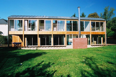 Aménagement d'une grande façade de maison marron moderne en bois et bardage à clin à un étage avec un toit en métal et un toit gris.