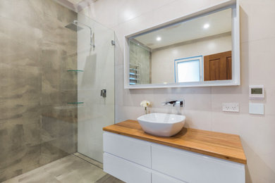 Large modern master bathroom in Sydney with flat-panel cabinets, white cabinets, a freestanding tub, an open shower, a two-piece toilet, gray tile, porcelain tile, white walls, porcelain floors, a vessel sink, wood benchtops, grey floor, an open shower and brown benchtops.