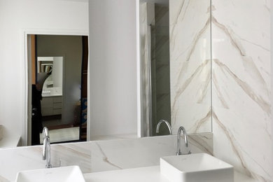 Aménagement d'une douche en alcôve principale contemporaine de taille moyenne avec un placard à porte affleurante, des portes de placard beiges, WC séparés, un carrelage blanc, des carreaux de porcelaine, un mur blanc, un sol en carrelage de céramique, un lavabo posé, un plan de toilette en stratifié, un sol marron, une cabine de douche à porte battante et un plan de toilette blanc.