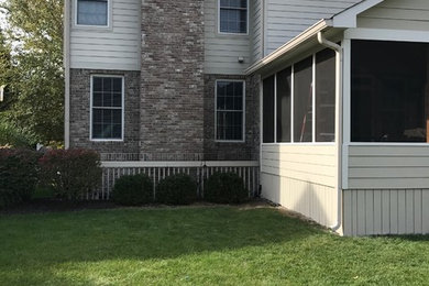 This is an example of a mid-sized traditional screened-in back porch design in Indianapolis with a roof extension.