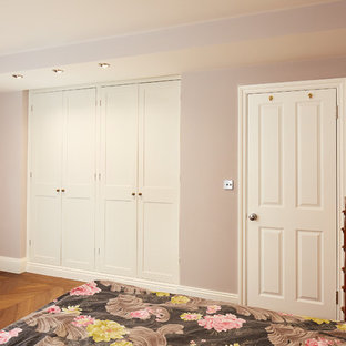 Small contemporary look-out basement in London with pink walls, light hardwood flooring, no fireplace and brown floors.