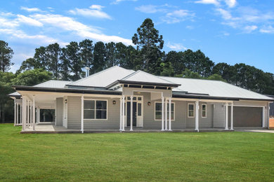 Large traditional one-storey house exterior in Brisbane with concrete fiberboard siding, a hip roof and a metal roof.