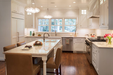 Photo of a traditional u-shaped eat-in kitchen in Charlotte with a farmhouse sink, beaded inset cabinets, white cabinets, granite benchtops, beige splashback, mosaic tile splashback, stainless steel appliances, medium hardwood floors and with island.