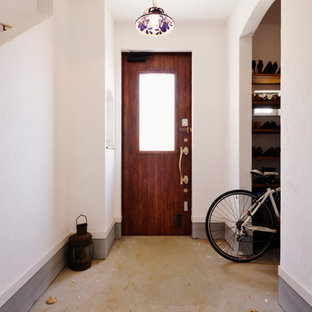 Modelo de hall bohemio con paredes blancas, suelo de cemento, puerta simple, puerta de madera oscura y suelo gris