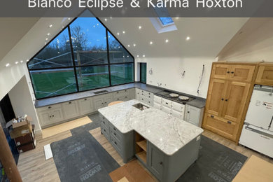 This is an example of an expansive contemporary l-shaped open plan kitchen in Other with grey splashback, an island, grey worktops and quartz worktops.