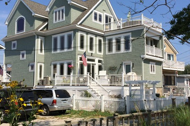 Large beach style green three-story vinyl exterior home photo in New York with a shingle roof