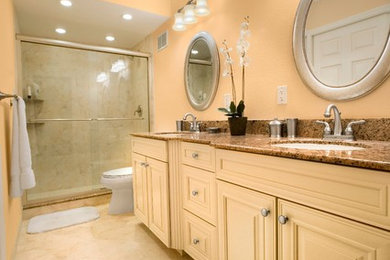 Small transitional master beige tile and porcelain tile porcelain tile alcove shower photo in Tampa with an undermount sink, raised-panel cabinets, beige cabinets, granite countertops, a two-piece toilet and orange walls