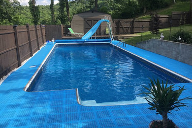 Diseño de piscina con tobogán clásica de tamaño medio rectangular en patio trasero con suelo de baldosas