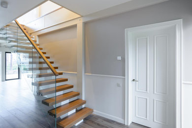 Foto de escalera recta actual de tamaño medio sin contrahuella con escalones de madera y barandilla de vidrio