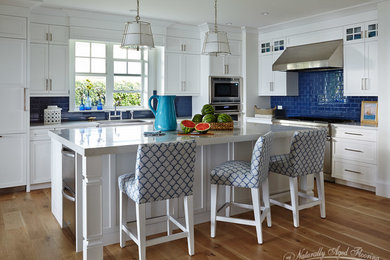 Open concept kitchen - transitional l-shaped light wood floor open concept kitchen idea in Tampa with a farmhouse sink, shaker cabinets, white cabinets, quartz countertops, blue backsplash, ceramic backsplash, stainless steel appliances and an island