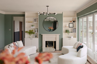 This is an example of an expansive contemporary formal open plan living room in London with green walls, medium hardwood flooring, a standard fireplace, a stone fireplace surround, brown floors and a chimney breast.