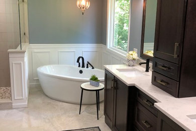 This is an example of a mid-sized transitional master bathroom in Cincinnati with shaker cabinets, dark wood cabinets, a freestanding tub, beige tile, porcelain tile, grey walls, ceramic floors, an undermount sink, quartzite benchtops, beige floor, a hinged shower door and turquoise benchtops.