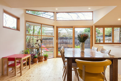 This is an example of a small contemporary open plan dining in Melbourne with white walls and light hardwood floors.