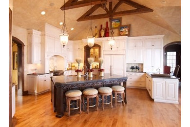 Example of a large classic u-shaped medium tone wood floor open concept kitchen design in Other with an undermount sink, raised-panel cabinets, distressed cabinets, granite countertops, beige backsplash, stone tile backsplash, paneled appliances and an island