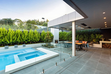 Large modern backyard custom-shaped pool in Melbourne with natural stone pavers.