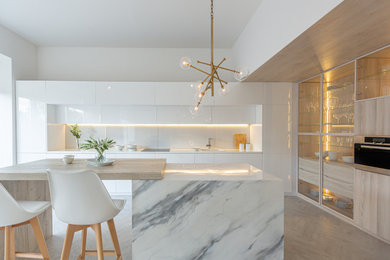Inspiration for a contemporary l-shaped gray floor kitchen remodel in San Francisco with a drop-in sink, flat-panel cabinets, white cabinets, white backsplash, stainless steel appliances, an island and white countertops