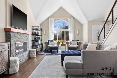 Example of a mid-sized trendy open concept medium tone wood floor, brown floor and vaulted ceiling living room design in Milwaukee with no tv, beige walls, a standard fireplace and a stacked stone fireplace