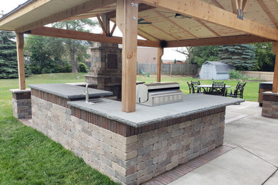 Inspiration for a mid-sized traditional backyard patio in Milwaukee with an outdoor kitchen, concrete slab and a pergola.