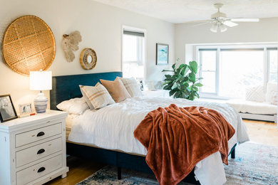 Modelo de dormitorio principal costero de tamaño medio sin chimenea con paredes beige y suelo de madera clara