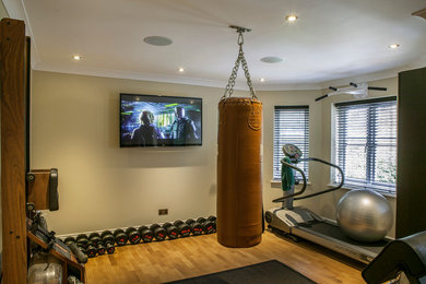 This is an example of a small eclectic multipurpose gym in London with beige walls and medium hardwood floors.