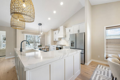 Inspiration for a mid-sized contemporary medium tone wood floor kitchen remodel in Cleveland with an undermount sink, shaker cabinets, white cabinets, quartz countertops, white backsplash, quartz backsplash, stainless steel appliances, an island and white countertops