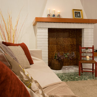 This is an example of a mediterranean open plan living room in Valencia with a standard fireplace, a brick fireplace surround and green floors.