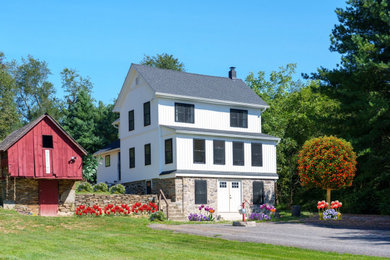 Large farmhouse white three-story stone and board and batten house exterior photo in Baltimore with a shingle roof and a black roof