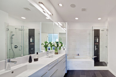 Large contemporary master bathroom in Austin with flat-panel cabinets, white cabinets, a drop-in tub, a corner shower, a two-piece toilet, black and white tile, stone tile, white walls, slate floors, solid surface benchtops and a drop-in sink.
