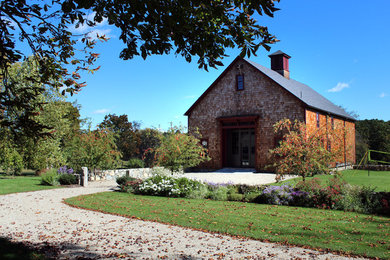 This is an example of a large farmhouse full sun backyard stone landscaping in Boston for spring.