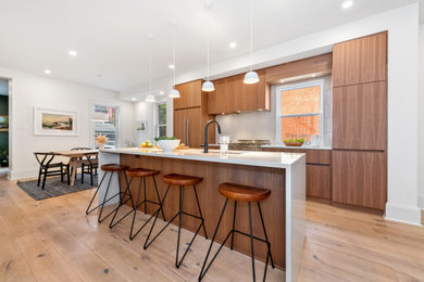 Inspiration for a mid-sized contemporary single-wall light wood floor and brown floor eat-in kitchen remodel in Ottawa with an undermount sink, flat-panel cabinets, stainless steel appliances, an island and white countertops