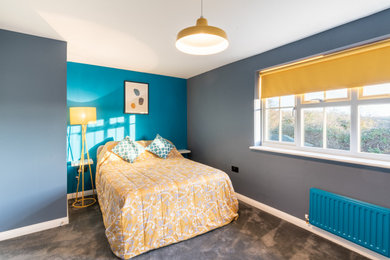 Photo of a medium sized contemporary guest and grey and teal bedroom in Kent with blue walls, carpet, grey floors and a feature wall.
