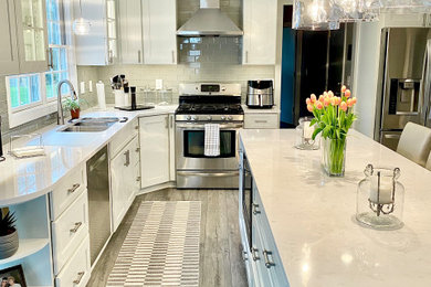 Inspiration for a mid-sized contemporary galley gray floor and light wood floor eat-in kitchen remodel in Cleveland with white cabinets, white backsplash, stainless steel appliances, an island, white countertops, a farmhouse sink, shaker cabinets, quartzite countertops and ceramic backsplash