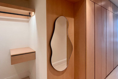 Mid-sized minimalist gender-neutral light wood floor and beige floor built-in closet photo in New York with flat-panel cabinets and light wood cabinets