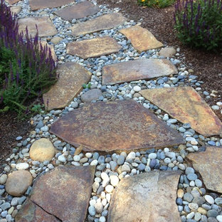 Cette image montre un petit jardin avant chalet avec une entrée ou une allée de jardin, une exposition ensoleillée et des pavés en pierre naturelle.