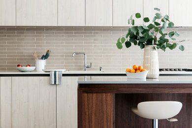 Open concept kitchen - mid-sized transitional l-shaped medium tone wood floor and gray floor open concept kitchen idea in San Francisco with an undermount sink, flat-panel cabinets, dark wood cabinets, quartz countertops, gray backsplash, subway tile backsplash, stainless steel appliances, an island and gray countertops