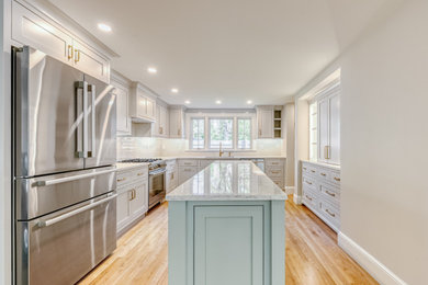 Open concept kitchen - u-shaped medium tone wood floor and beige floor open concept kitchen idea in Boston with a drop-in sink, recessed-panel cabinets, white cabinets, quartz countertops, white backsplash, porcelain backsplash, stainless steel appliances, an island and white countertops