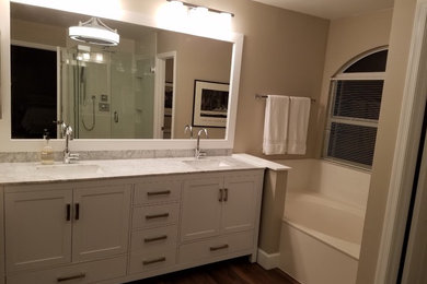 Example of a mid-sized trendy master white tile and subway tile dark wood floor and brown floor bathroom design in Miami with recessed-panel cabinets, white cabinets, a two-piece toilet, beige walls, an undermount sink, marble countertops, a hinged shower door and gray countertops
