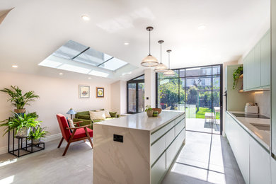 Inspiration for a medium sized modern single-wall open plan kitchen in London with an integrated sink, flat-panel cabinets, green cabinets, quartz worktops, white splashback, engineered quartz splashback, integrated appliances, cement flooring, an island, grey floors and white worktops.