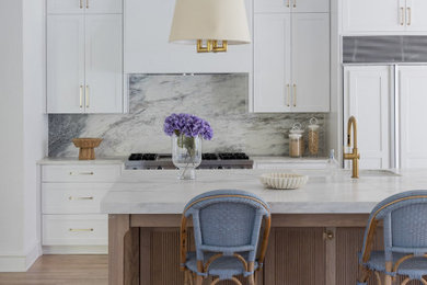 Example of a huge transitional single-wall light wood floor and brown floor eat-in kitchen design in Dallas with an undermount sink, shaker cabinets, white cabinets, quartzite countertops, white backsplash, stone slab backsplash, stainless steel appliances, an island and white countertops