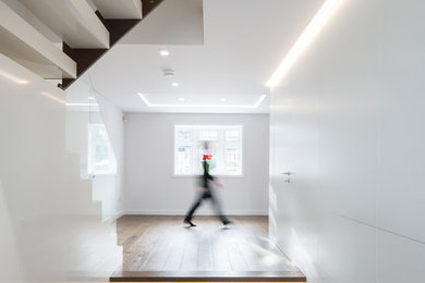 Mid-sized contemporary hallway in London with white walls and dark hardwood floors.