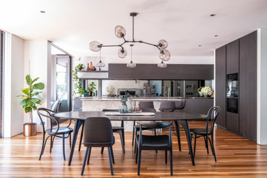 シドニーにある高級なコンテンポラリースタイルのおしゃれなキッチン (オープンシェルフ、ステンレスカウンター、ミラータイルのキッチンパネル、黒い調理設備、茶色い床) の写真