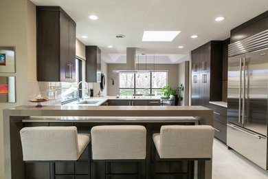 This is an example of an expansive modern u-shaped open plan kitchen in Albuquerque with an undermount sink, flat-panel cabinets, dark wood cabinets, quartzite benchtops, white splashback, subway tile splashback, stainless steel appliances, porcelain floors, a peninsula, beige floor and beige benchtop.