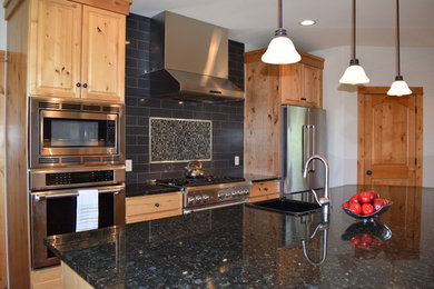 Large elegant u-shaped medium tone wood floor kitchen photo in Other with raised-panel cabinets, medium tone wood cabinets, black backsplash, ceramic backsplash, stainless steel appliances, an island and granite countertops