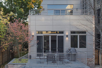 This is an example of a mid-sized contemporary three-storey grey exterior in Chicago with mixed siding and a flat roof.