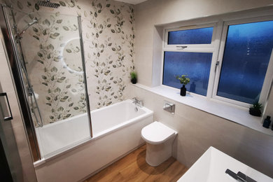 This is an example of a medium sized contemporary family bathroom in West Midlands with green cabinets, a built-in bath, a shower/bath combination, a one-piece toilet, white tiles, ceramic tiles, vinyl flooring, brown floors, an enclosed toilet, a single sink and a floating vanity unit.