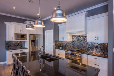 Eat-in kitchen - mid-sized transitional l-shaped porcelain tile eat-in kitchen idea in Calgary with a double-bowl sink, shaker cabinets, white cabinets, multicolored backsplash, mosaic tile backsplash, stainless steel appliances, an island and quartz countertops
