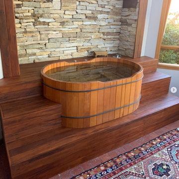 Oval wooden bathtub embedded in deck