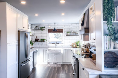 Mid-sized elegant u-shaped dark wood floor and brown floor eat-in kitchen photo in Calgary with a farmhouse sink, shaker cabinets, white cabinets, quartzite countertops, white backsplash, subway tile backsplash, black appliances, no island and white countertops